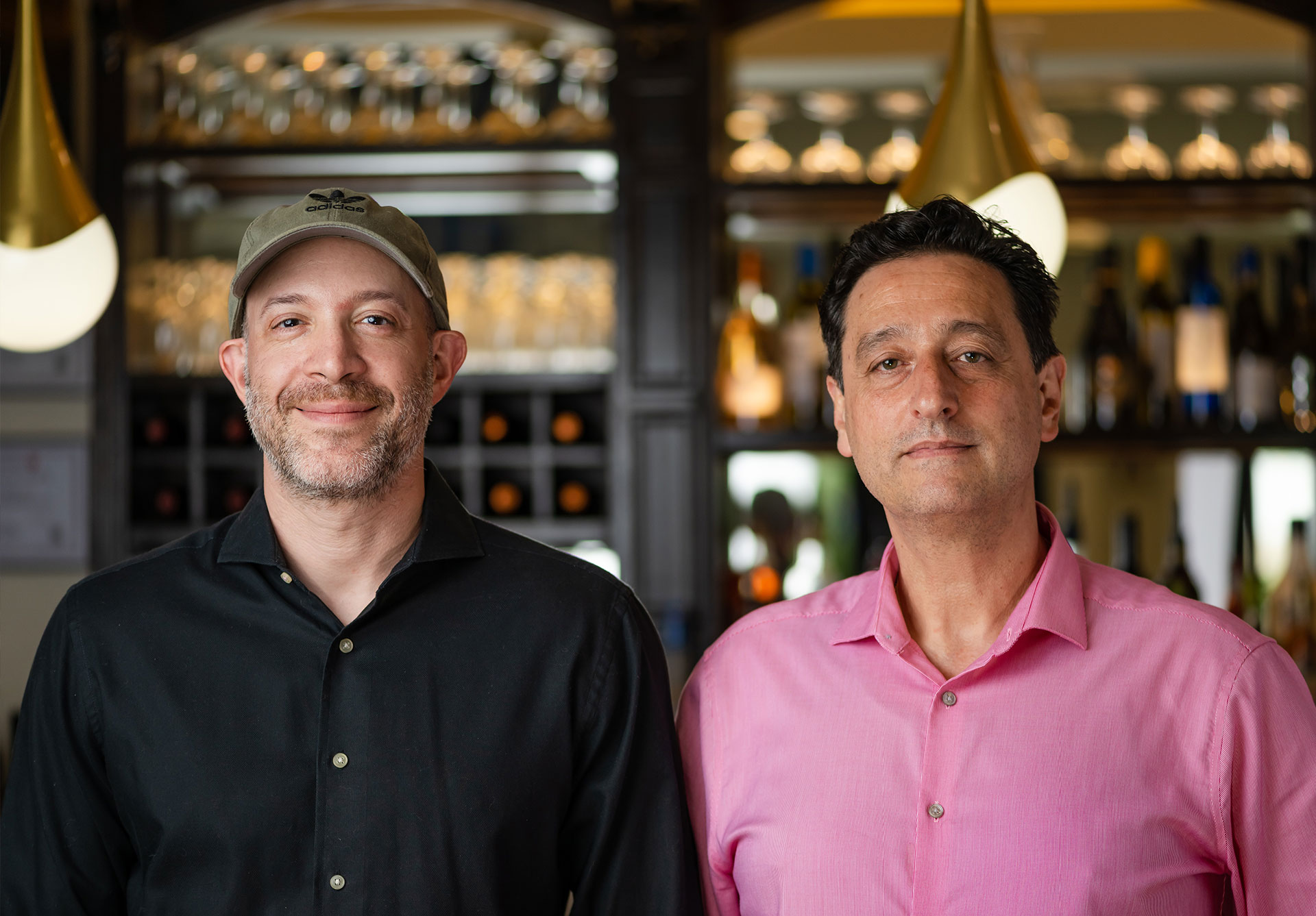 EMTOG-Header-About-Us-1 Two men standing in front of a restaurant bar
